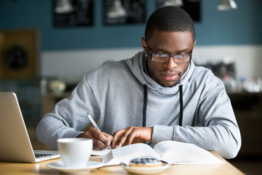 Student wearing glasses focusing on a text book while studying